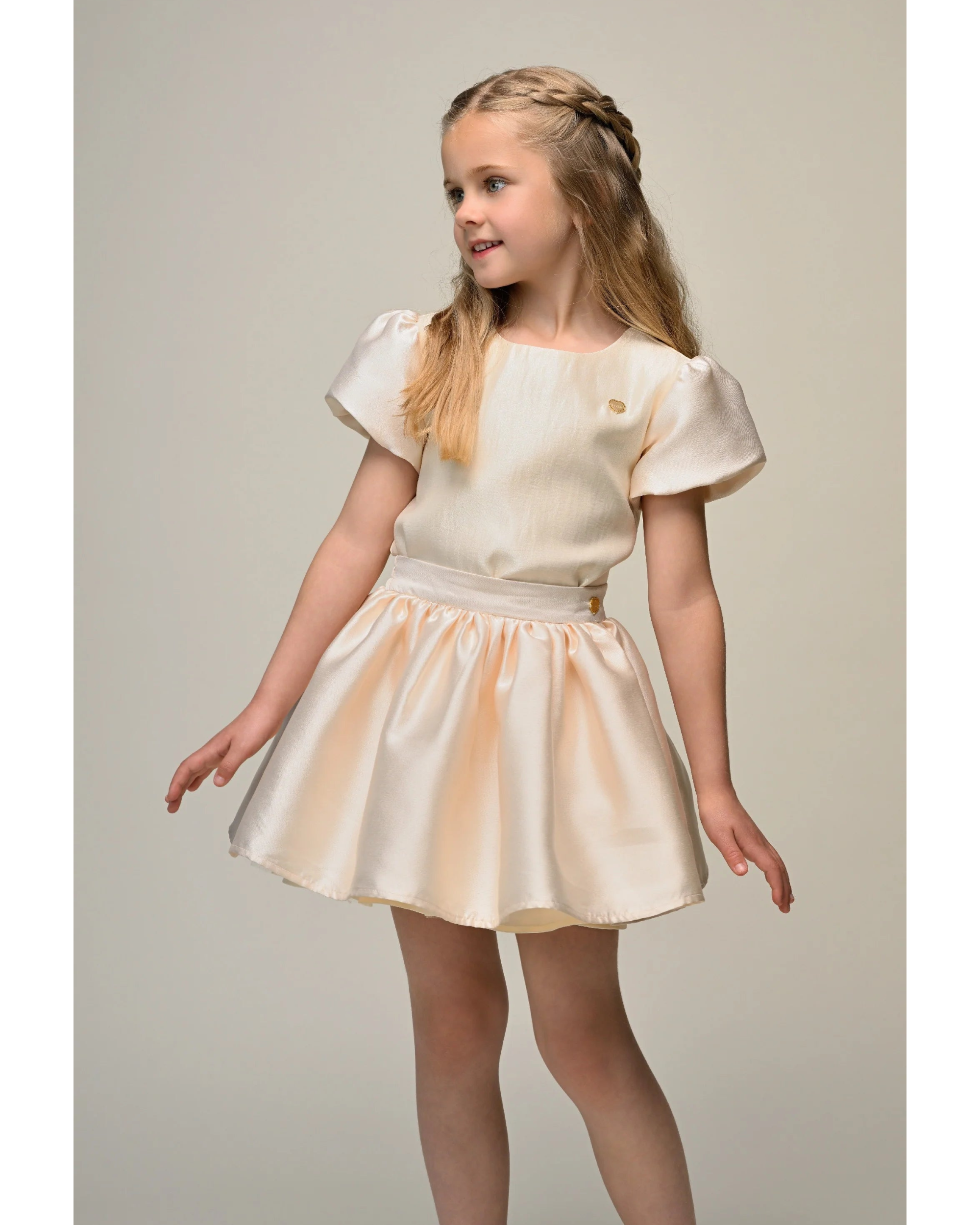 Young girl wearing a beige top and skirt dress by Le Chic