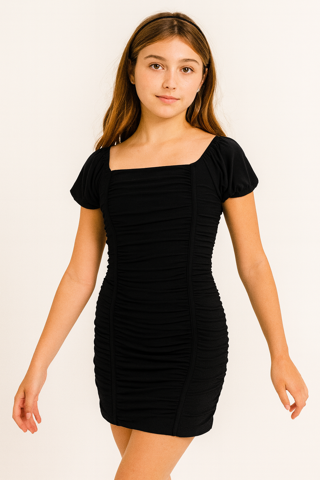 tween girl wearing a rouched fitted black dress against a plain background