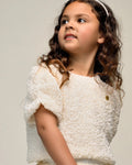 Young girl wearing a white textured top and skirt  by Le Chic