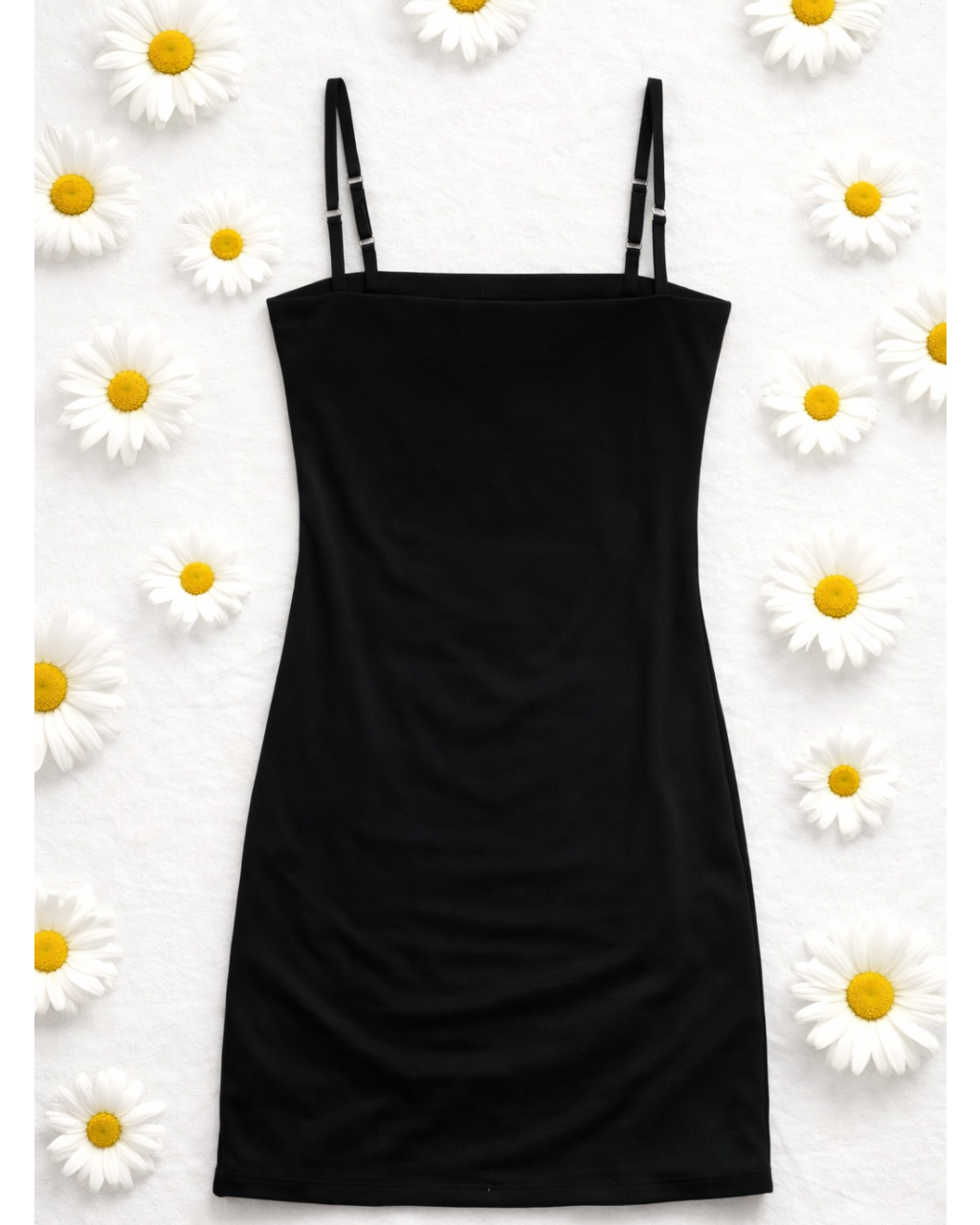 Black slip dress on a white background with daisies