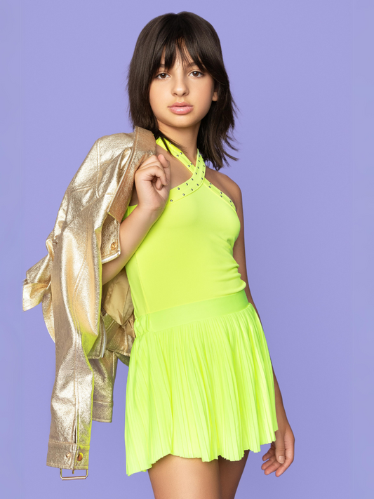 A girl wearing a yellow halter top, yellow pleated skirt, and gold moto jacket.